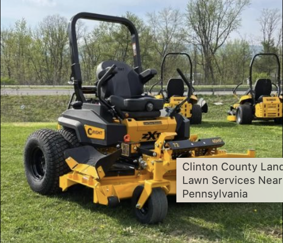 Yellow and black zero-turn radius mower on grass with trees and additional mowers in background